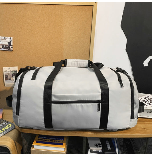 White duffel bag with black straps on a wooden surface