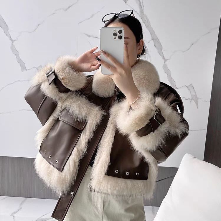 Person wearing a brown leather jacket with white fur trim, taking a mirror selfie.