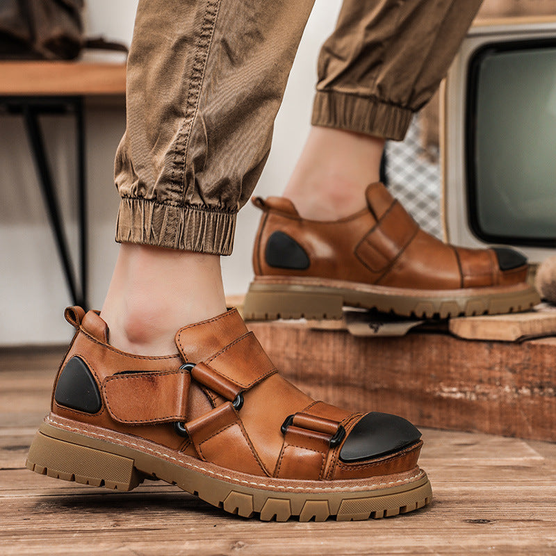 Brown sandals with black accents worn by a person on a wooden floor.