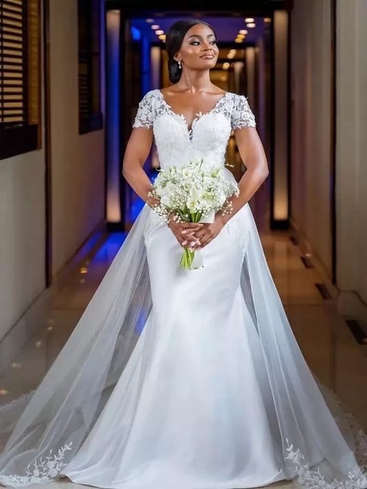 Woman in a white wedding dress holding a bouquet in an indoor setting