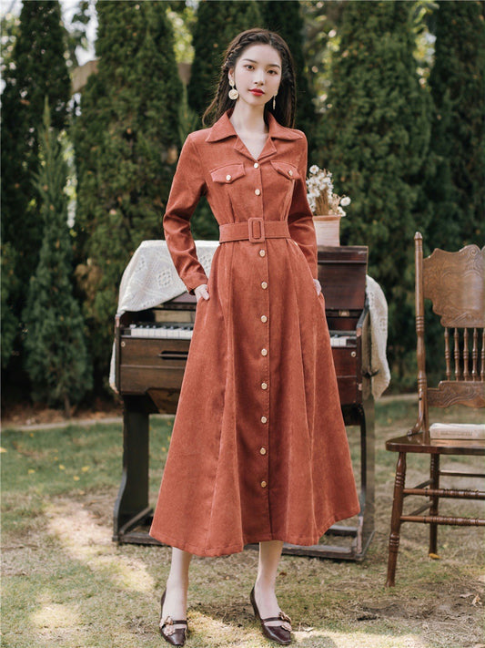 Woman in a long rust-colored dress standing outdoors with a piano and chair in the background. by millivan