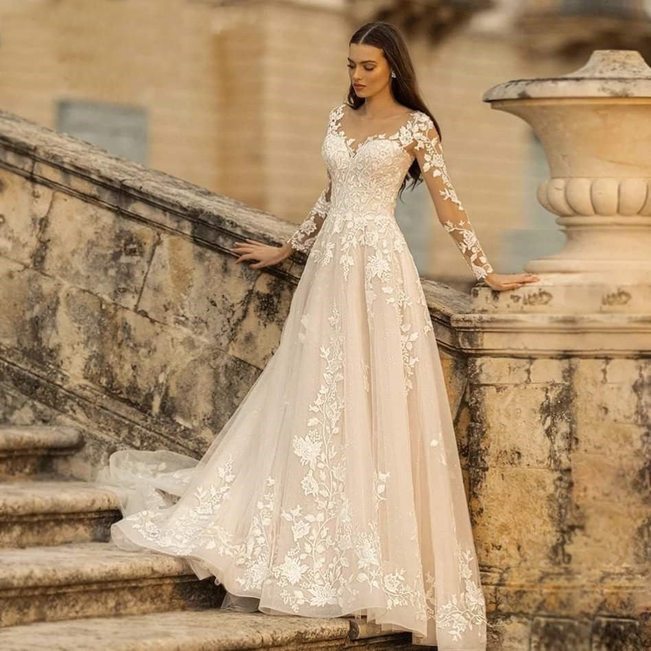 Woman in a white lace wedding dress standing on stone steps.