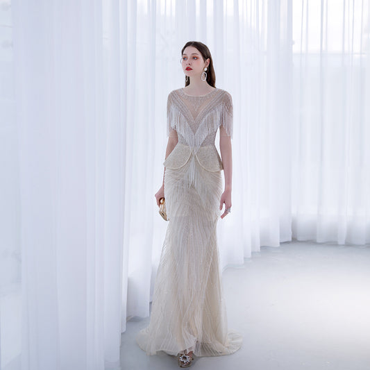 Woman wearing a long, elegant dress with intricate detailing in a softly lit room.