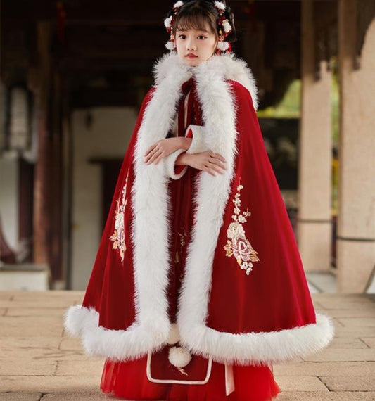 Traditional red garment with white fur trim worn by a person, set against an architectural background.