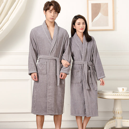 Two people wearing gray robes in a room with a table and picture frame.