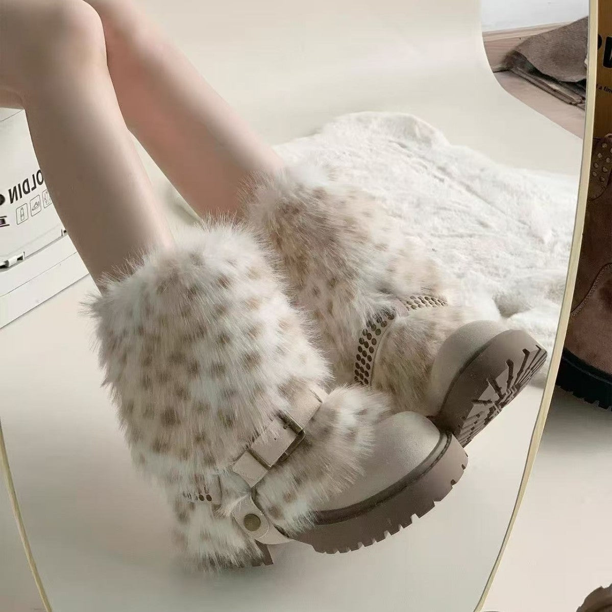 White furry boots with brown accents on a white surface