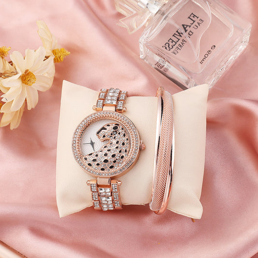 Rose gold watch and bracelet set on a pink fabric background with flowers and perfume bottle.