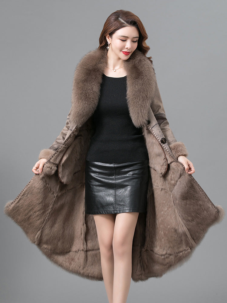 Woman wearing a long brown fur coat on a gray background