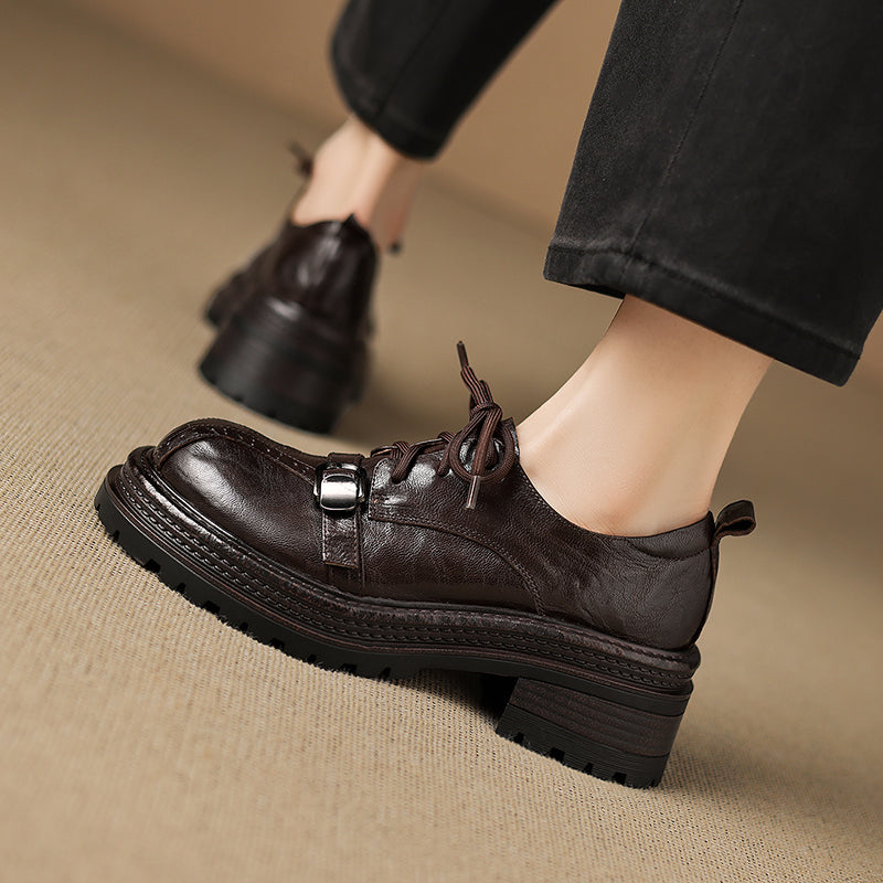 Brown leather shoes worn on a beige surface