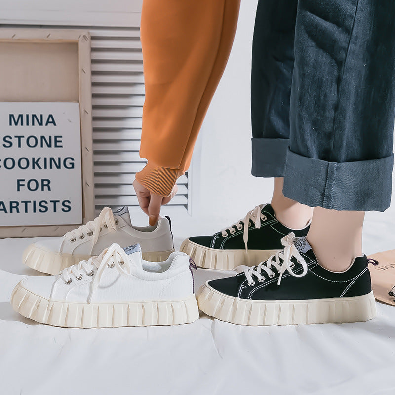 Two pairs of sneakers, one white and one black, on a light surface with a blurred background.