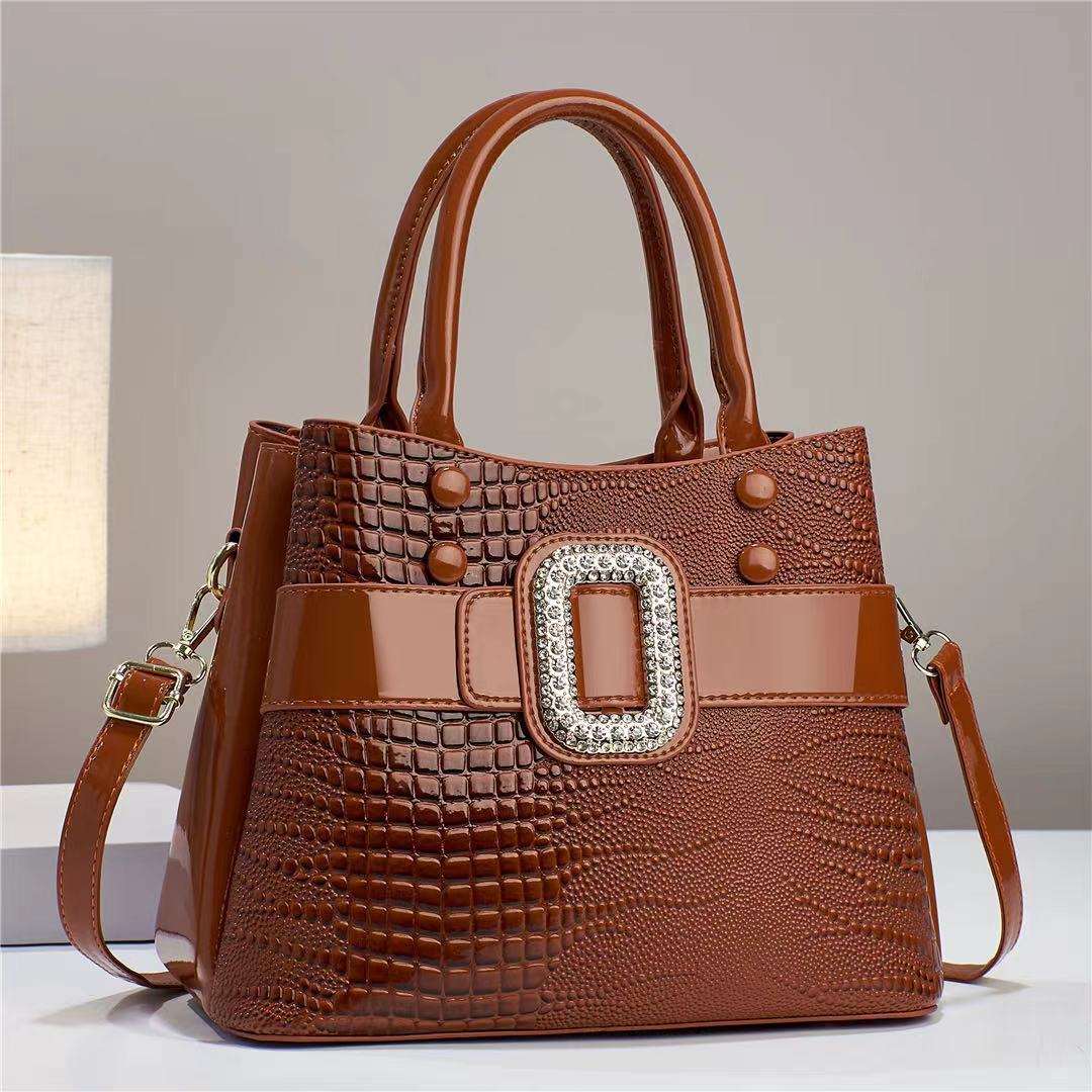 Brown textured handbag with a decorative buckle on a neutral background