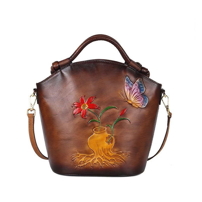 Brown leather handbag with floral and butterfly design on a white background