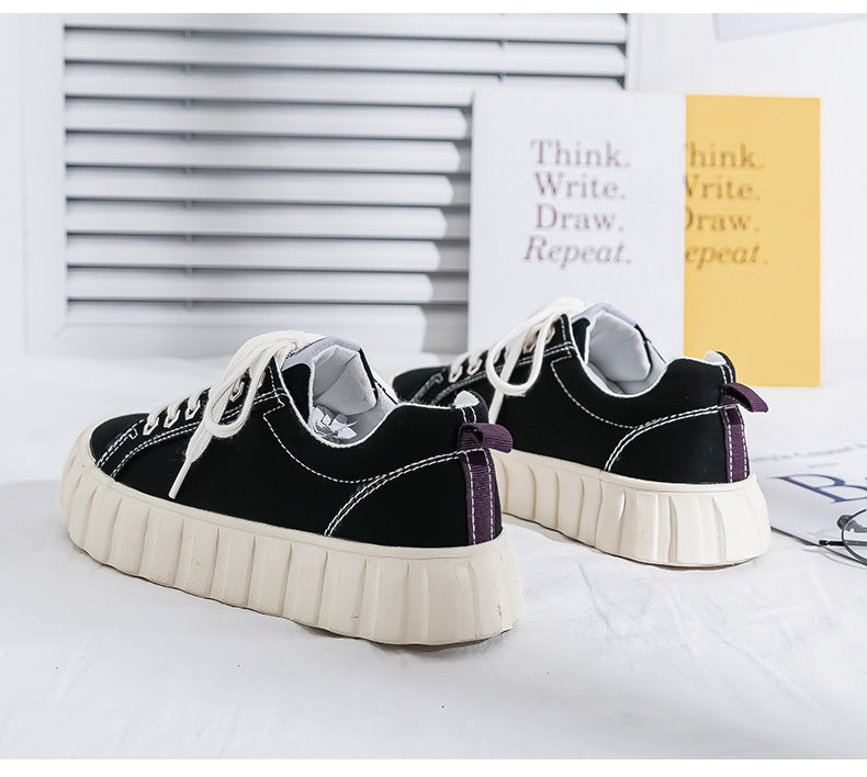 Black and white sneakers with purple accents on a white surface.