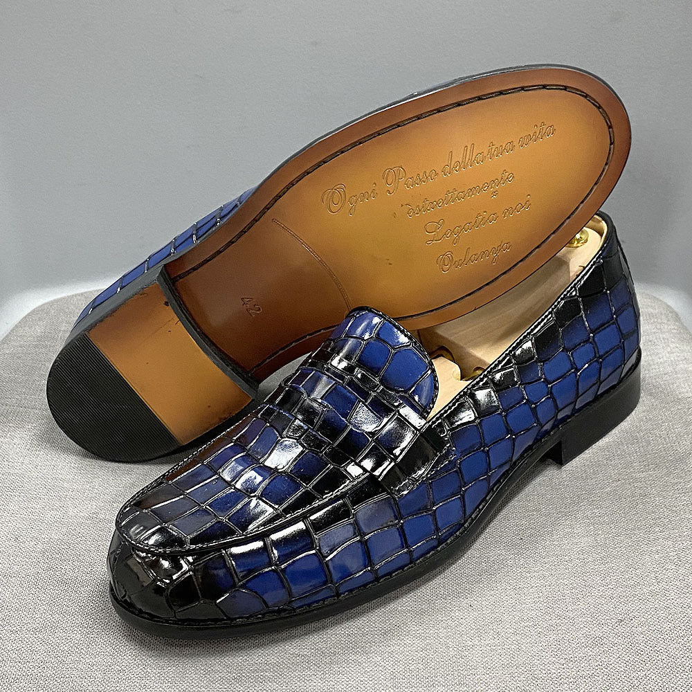 Blue woven loafer shoe with brown leather sole on a light gray background