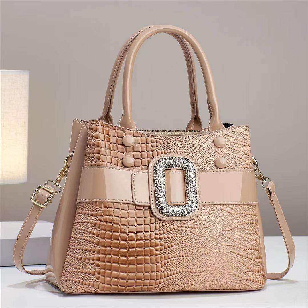 Beige handbag with textured pattern and decorative buckle on a neutral background