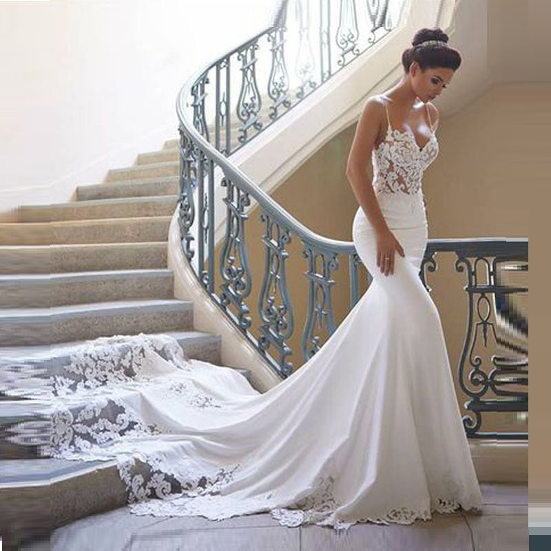 Woman in a white lace wedding dress standing on a staircase