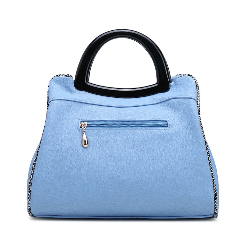 Light blue handbag with a black handle on a white background
