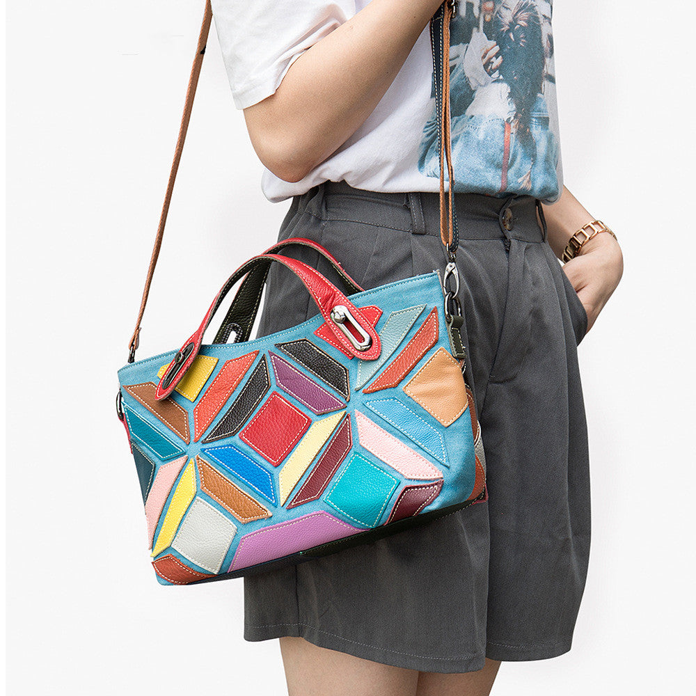 Person holding a colorful geometric-patterned handbag against a white background