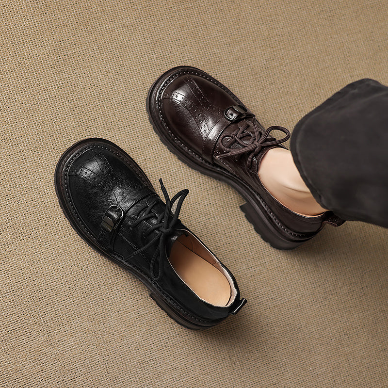 Pair of black and brown leather shoes on a textured beige surface