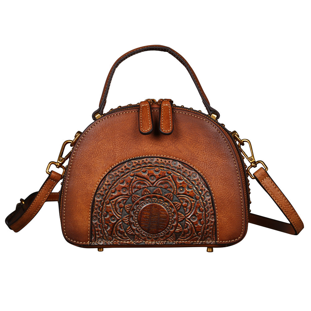 Brown leather handbag with intricate design on a white background