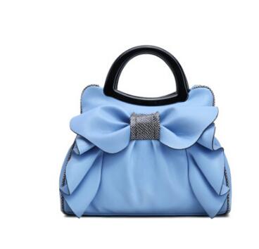 Blue handbag with a large bow and black handle on a white background