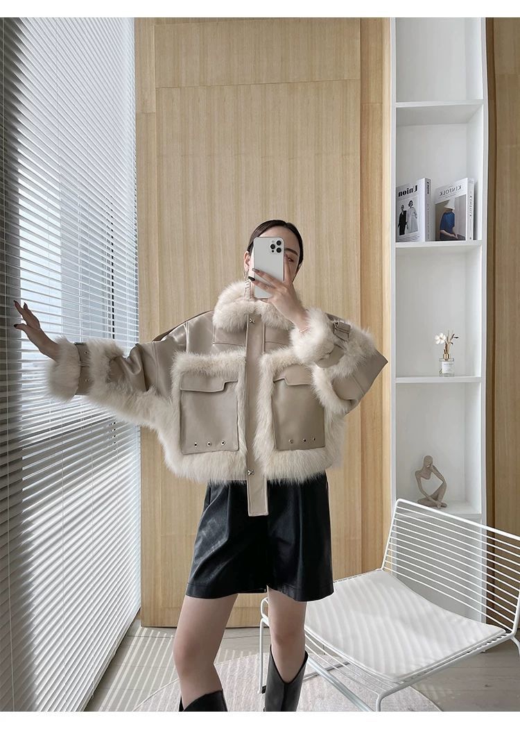 Person wearing a fur-trimmed jacket in a modern interior setting