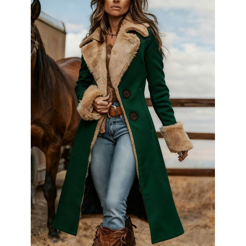 A woman wearing a long dark green coat with a beige faux-fur collar, lapels, and cuffs, paired with blue jeans and brown boots, standing in a rustic outdoor setting next to a horse.