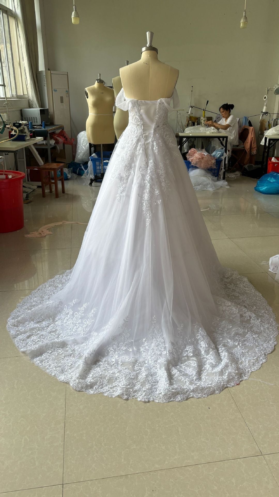 White wedding dress on a mannequin in a room with other mannequins and furniture.