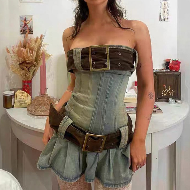 Woman wearing a denim dress with belt and buckle details in a room setting.