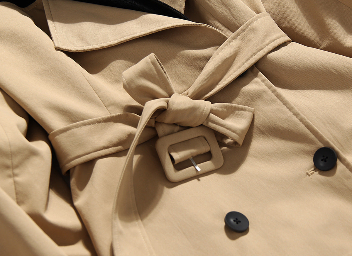 Close-up of a beige trench coat with a belt and buttons. by millivan