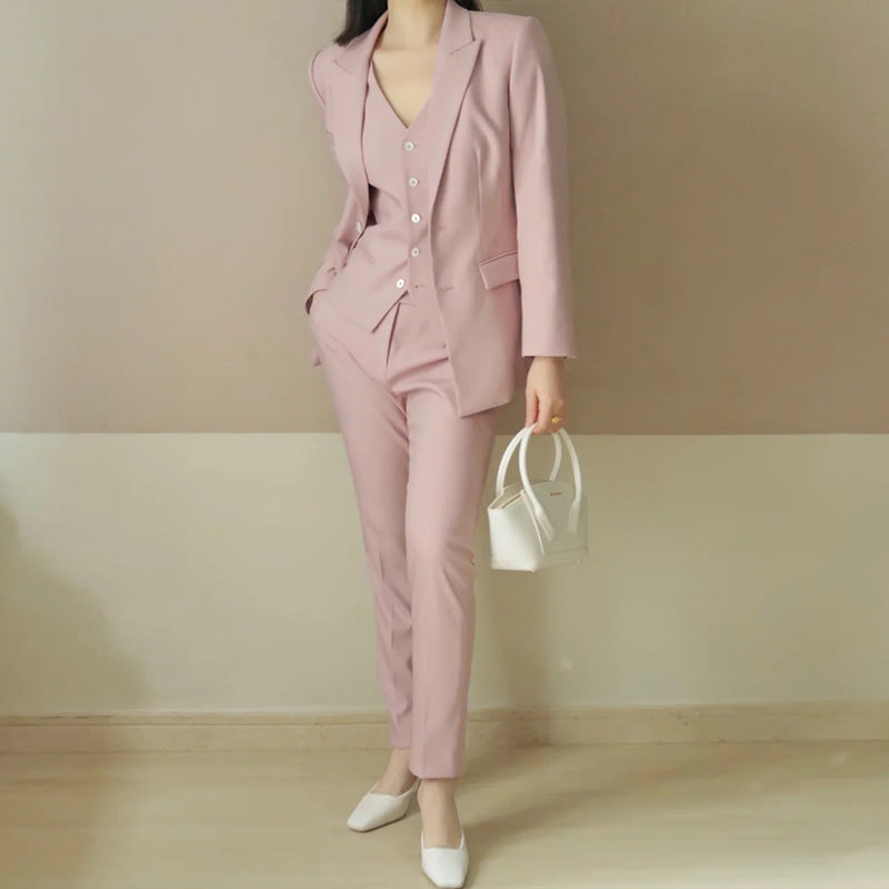 Person wearing a pink suit holding a white handbag against a plain background