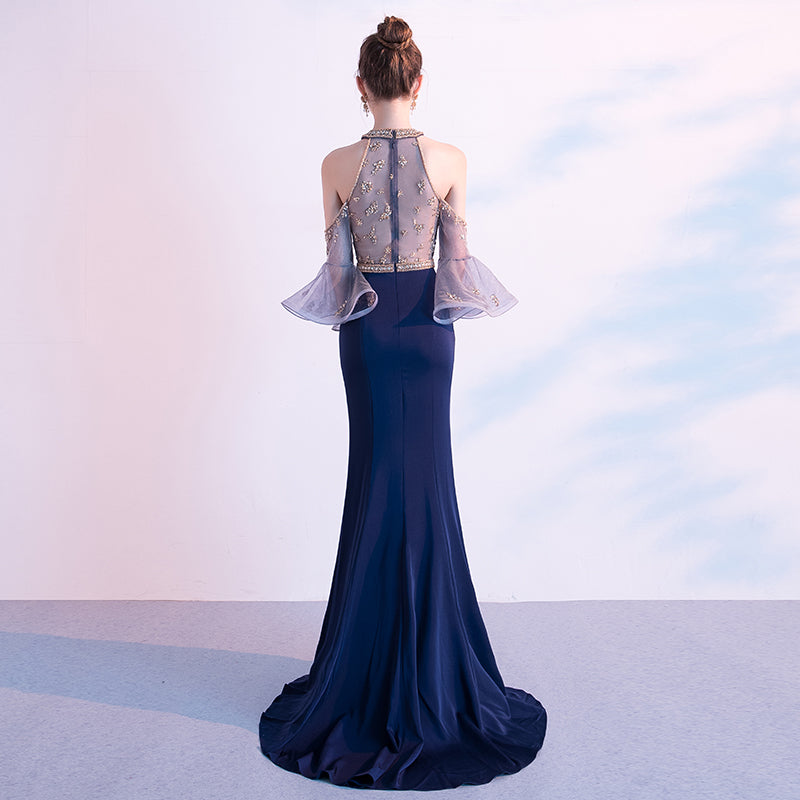 Navy blue evening gown with sheer sleeves against a light background