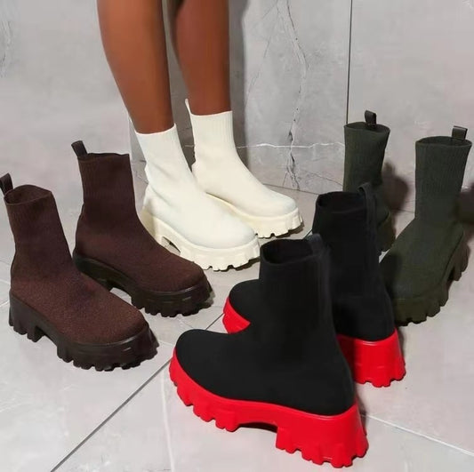 Black, brown, and red platform boots on a tiled floor.