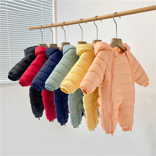 Row of colorful children's puffer jackets on hangers against a white wall.