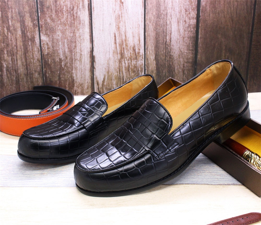 Black leather loafers with a textured pattern on a wooden floor.
