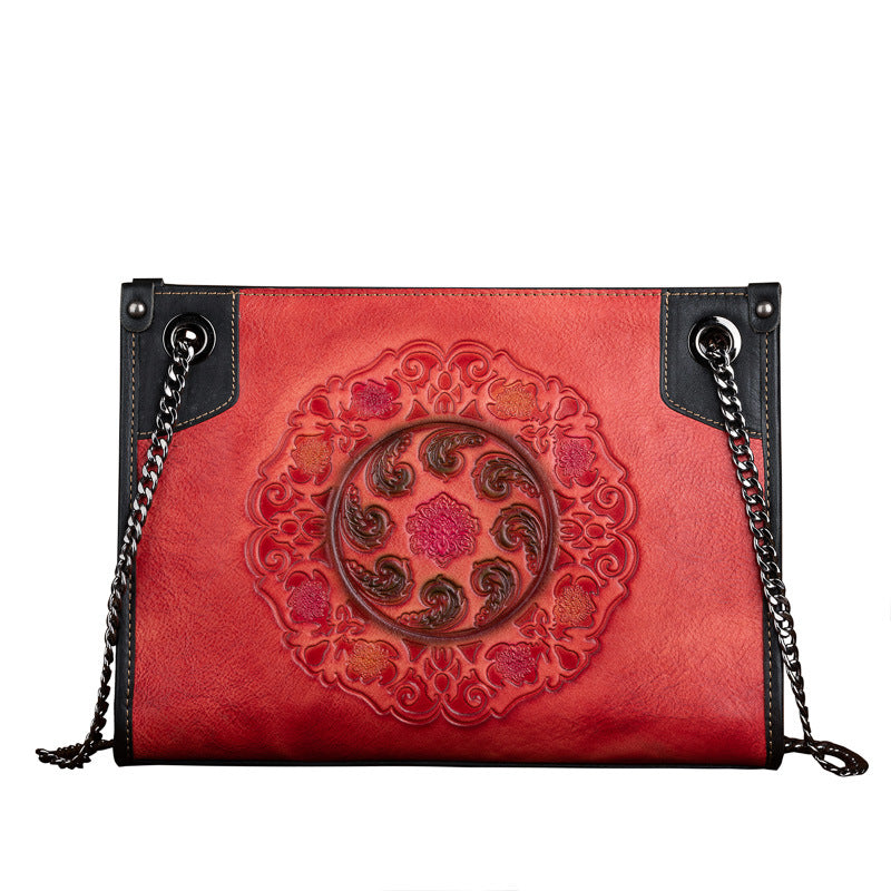 Red handbag with intricate design and black chain strap on a white background