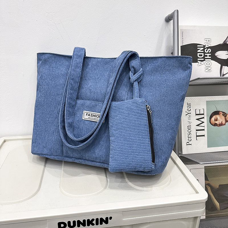 Blue tote bag with a smaller pouch on a white surface with a Dunkin' sign.