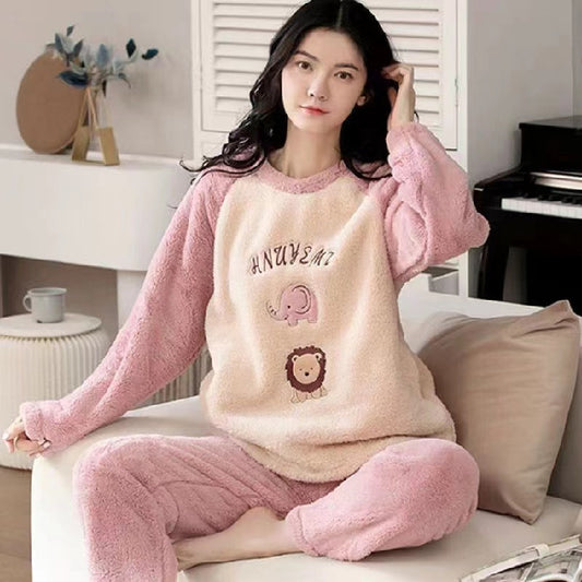Woman wearing a pink and beige fleece pajama set sitting on a couch.