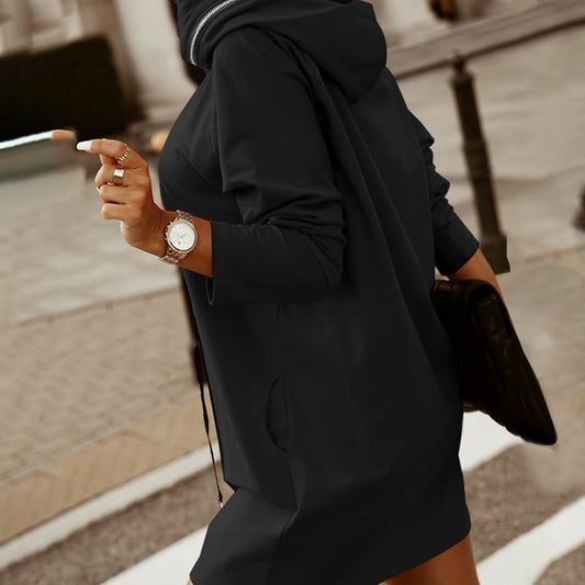 Person wearing a black hoodie and holding a phone on a street.