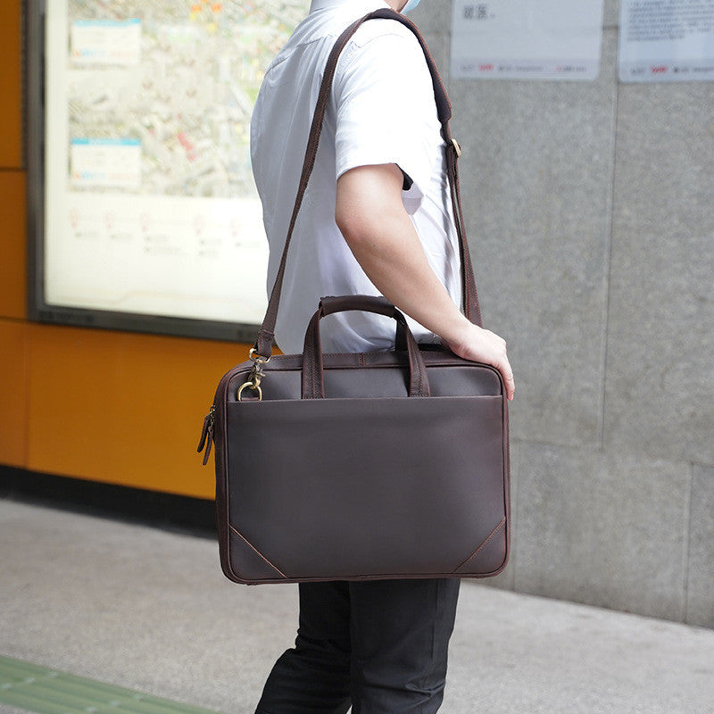 Person holding a brown leather briefcase in an urban setting