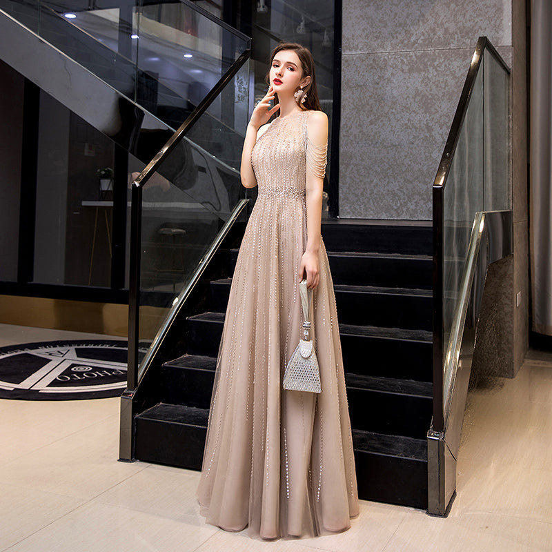 Woman in a beige evening gown standing in a stylish interior setting