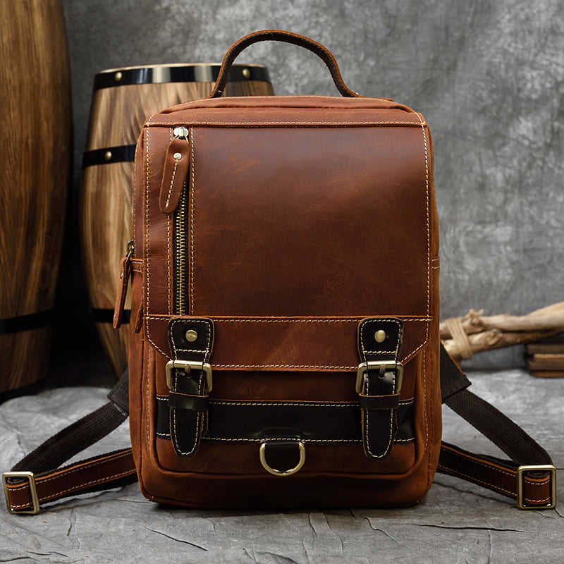 Brown leather backpack on a textured surface with wooden barrels in the background