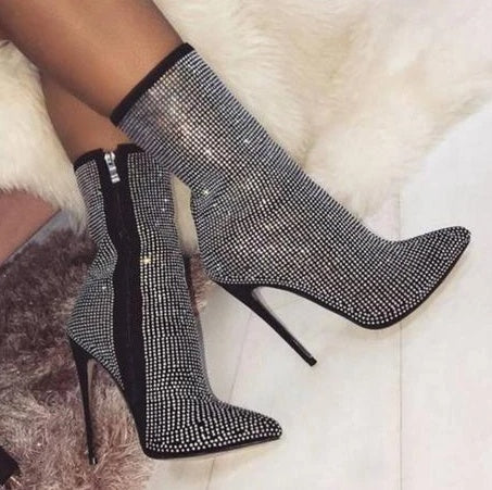 Black stiletto boots with rhinestone embellishments on a white fur surface