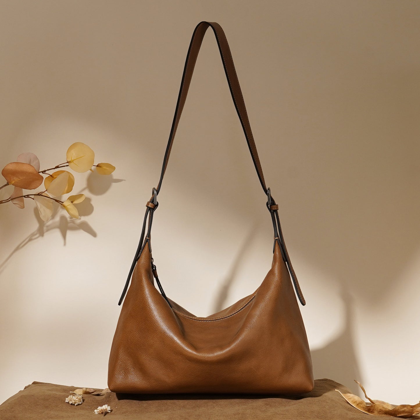 Brown leather handbag on a wooden surface with a neutral background