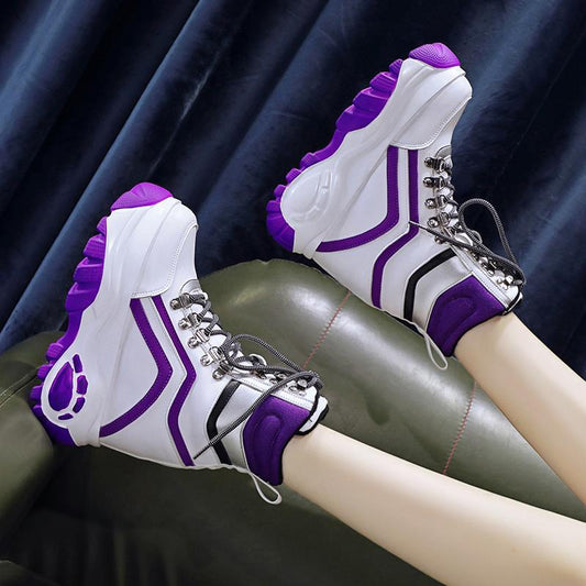 White sneakers with purple accents worn by a person sitting on a dark surface.