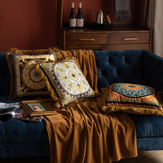 Decorative pillows and a blanket on a blue sofa with a wooden cabinet in the background.