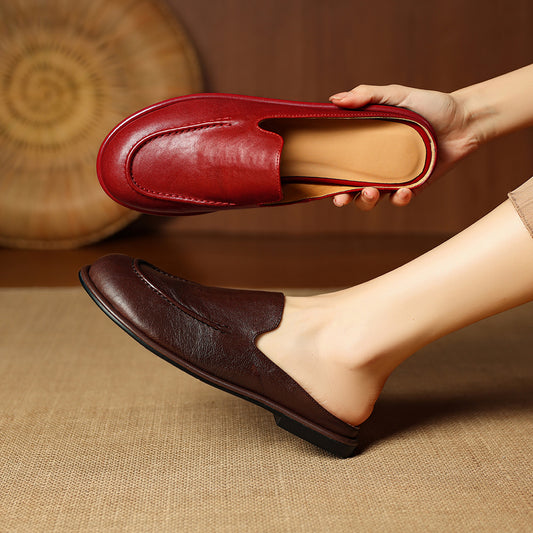 Person holding a red loafer shoe with a brown background