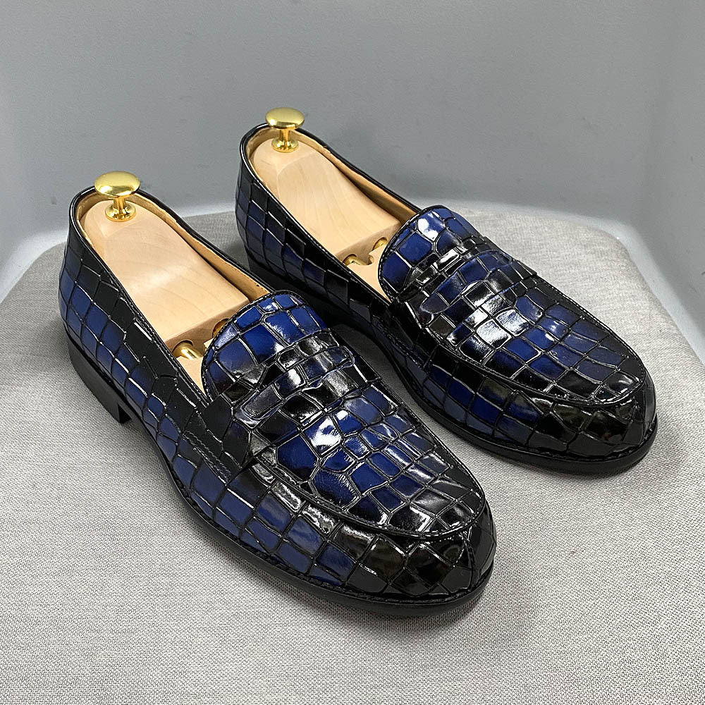 Pair of blue and black crocodile-patterned loafers on a light gray surface.