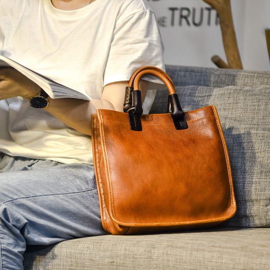 Brown leather handbag on a person's lap with a blurred background