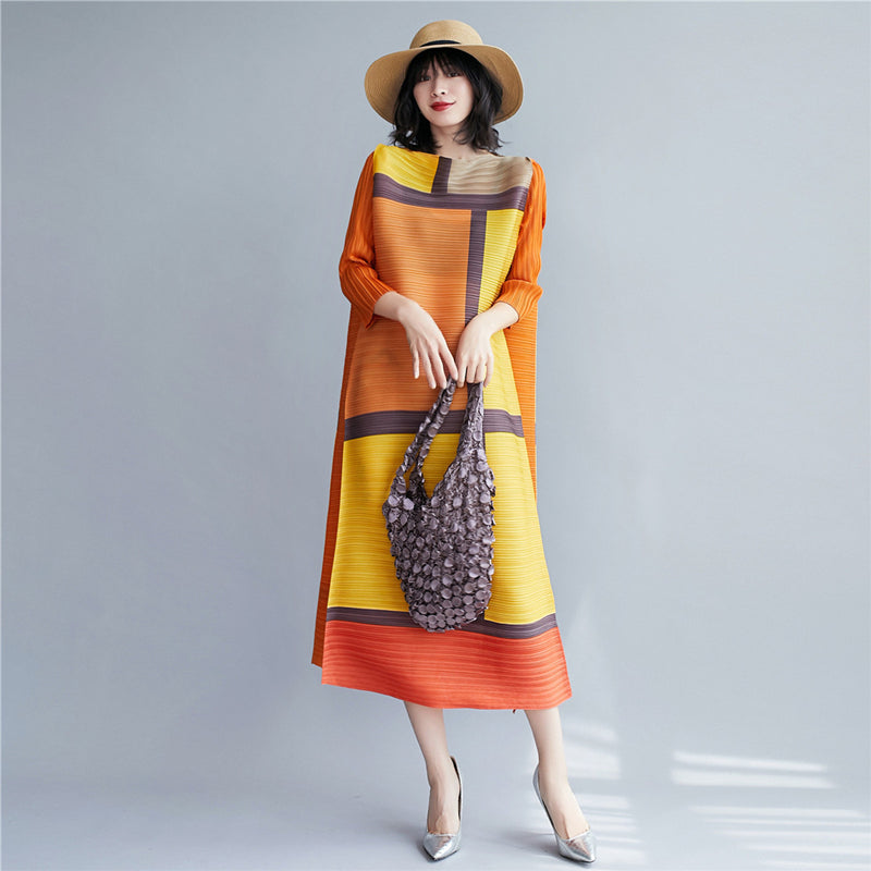 Woman wearing a colorful dress holding a handbag against a gray background